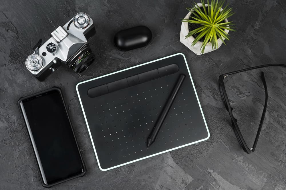 Bureau moderne avec tablette graphique, stylet et équipements créatifs incluant un stylo caméra discret