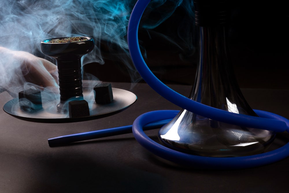 Un cendrier rond en verre et un briquet métallique posés sur une surface sombre, représentant des accessoires fumeurs essentiels