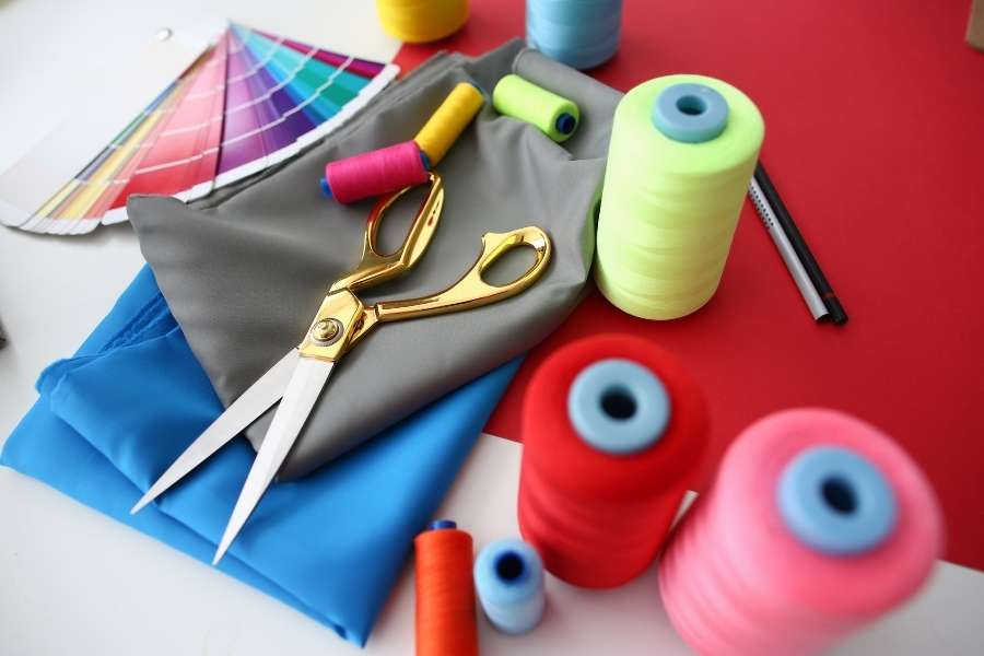 Matériel de couture coloré avec ciseaux dorés, tissus et bobines de fil