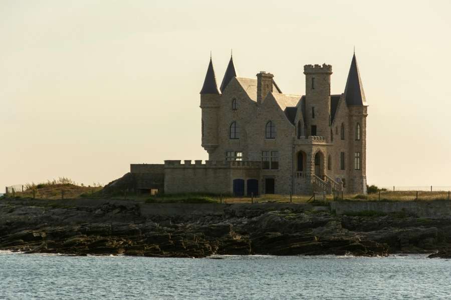 Manoir breton historique sur la côte au crépuscule Château breton en pierre avec tourelles face à la mer au coucher du soleil