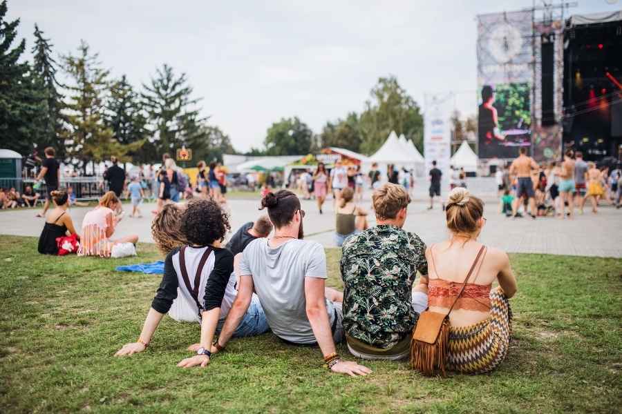 Groupe d'amis assis sur l'herbe regardant la scène lors d'un festival d'été en plein air