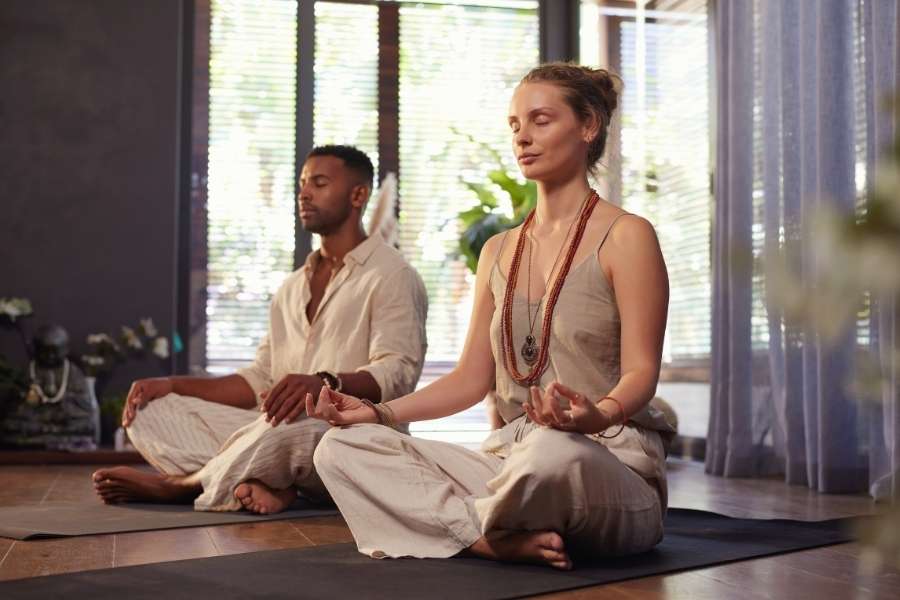 Couple méditant en position du lotus dans un intérieur lumineux et zen