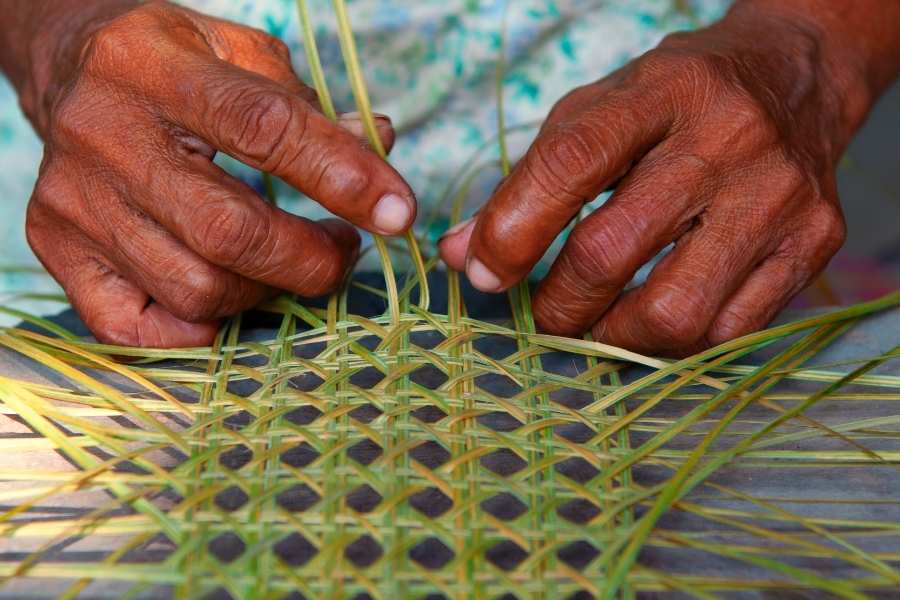 Mains d'artisan tressant des fibres végétales selon technique traditionnelle