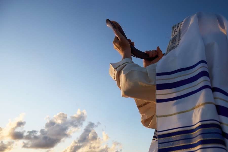 Homme en tallit juif priant au lever du soleil face au ciel