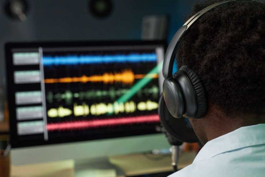 Production musicale et mixage audio sur station de travail numérique Producteur musical avec casque audio travaillant sur logiciel de production avec pistes colorées