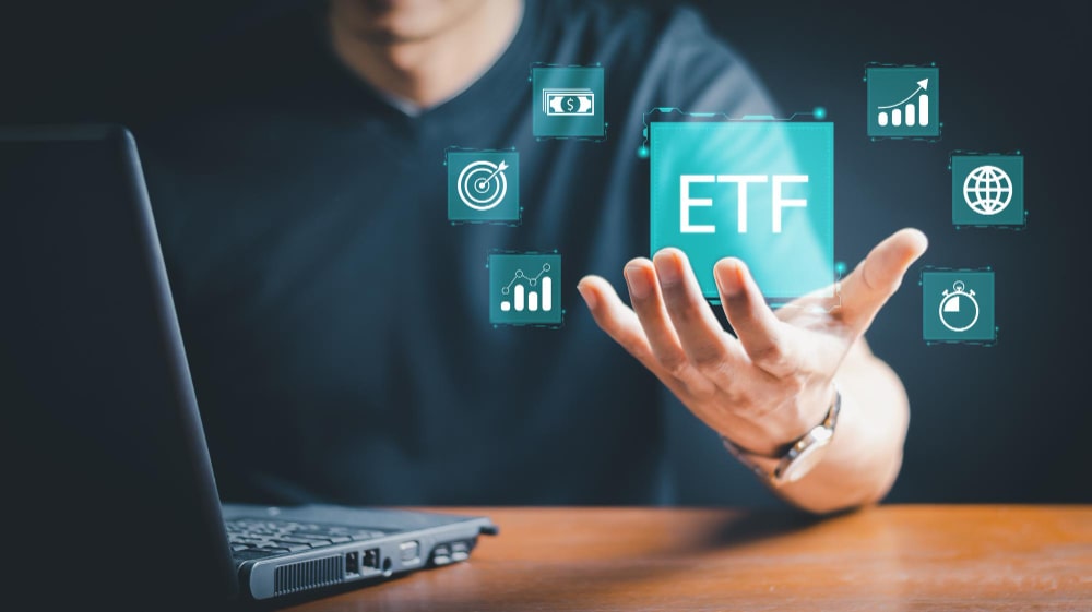 Homme devant un ordinateur portable, tenant une icône numérique ETF entourée de symboles d'investissement.