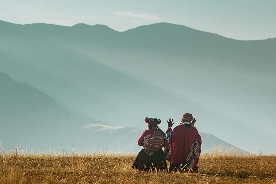 Deux femmes en costumes traditionnels andins contemplent les montagnes brumeuses