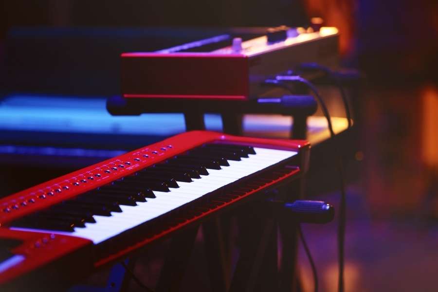Synthétiseur rouge illuminé par des lumières bleues et orangées sur une scène de concert