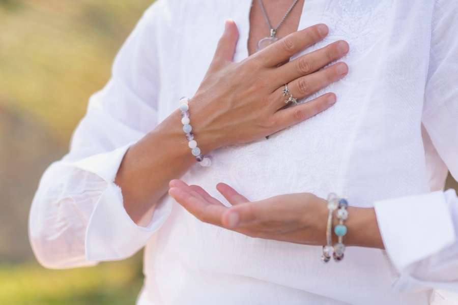 Femme en méditation posant les mains sur son cœur en pleine nature