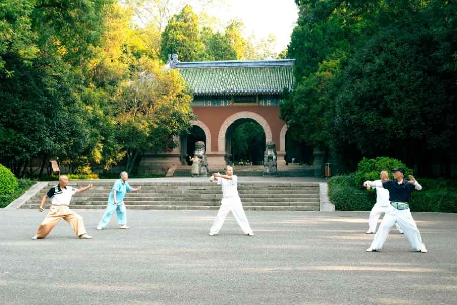 Pratiques spirituelles de tai-chi en plein air Groupe pratiquant le tai-chi devant un temple asiatique traditionnel