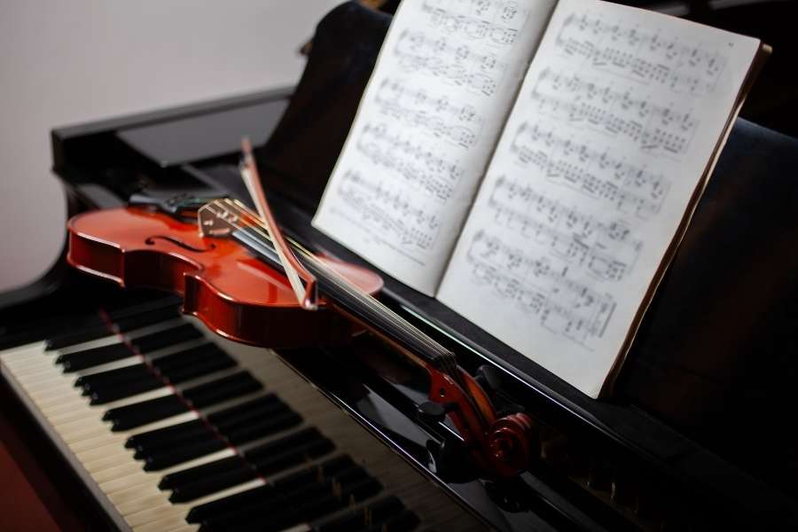 Violon posé sur un piano avec partition musicale ouverte prêt pour une répétition