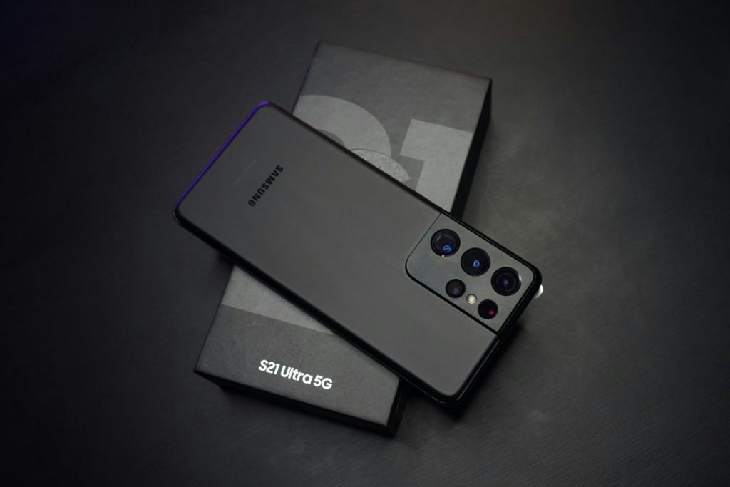 Un smartphone Samsung S21 Ultra 5G noir posé sur sa boîte, affichant son impressionnant module de cinq caméras.