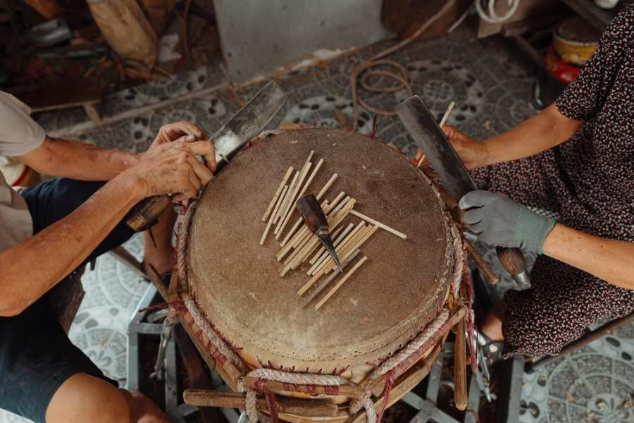 Création artisanale d’un tambour selon méthodes traditionnelles Artisans fabriquant un tambour traditionnel avec techniques manuelles ancestrales