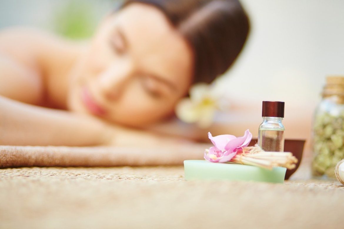 Femme détendue allongée lors d'un soin spa, illustrant les bienfaits massage contre le stress quotidien avec des huiles essentielles.