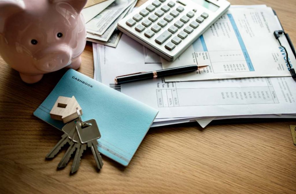 Une calculatrice, un porte-clés en forme de maison, une tirelire et des documents financiers posés sur une table pour simuler l'évolution taux crédit immobilier France.