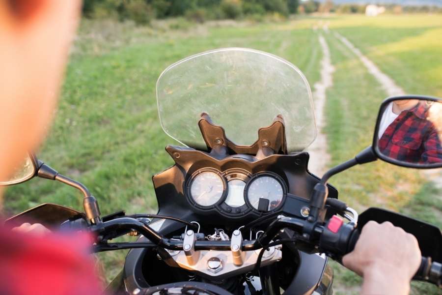 Un motard en chemise à carreaux est arrêté au guidon de sa moto face à une bulle moto transparente.