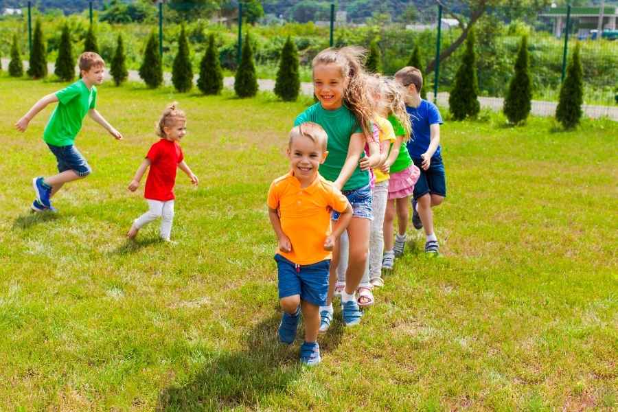 Un groupe d'enfants joyeux court dans un parc, profitant de l'un des meilleurs jeux d'extérieur pour se dépenser.