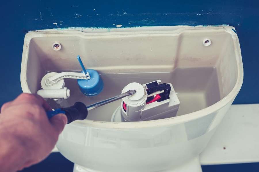 Gros plan sur l'intérieur d'un réservoir pour réparer une chasse d'eau.