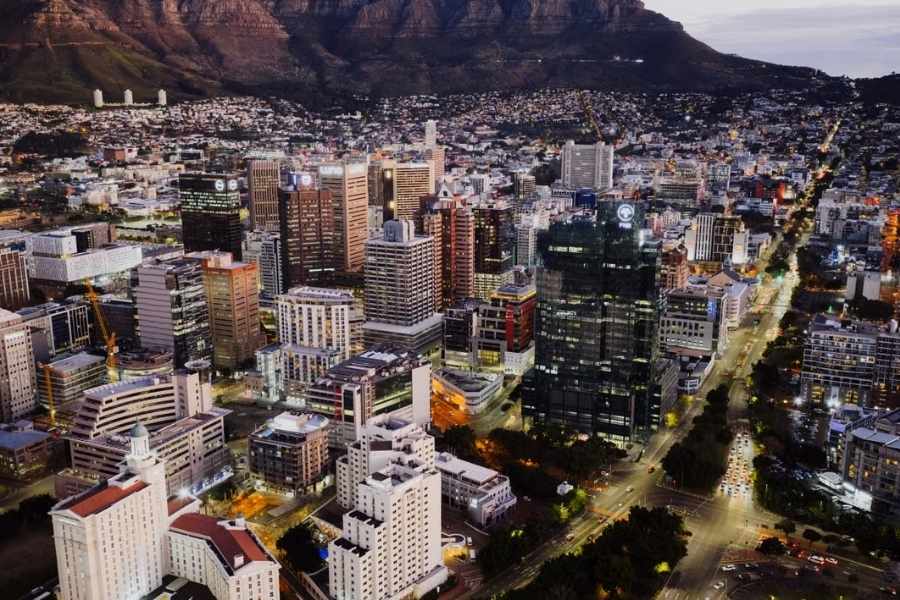 Vue nocturne d'une ville moderne au pied d'une montagne, symbolisant les enjeux liés à l'énergie propre en Afrique rurale.