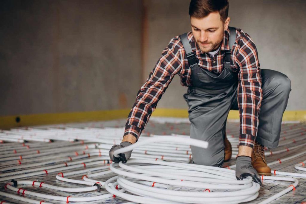 Un artisan prépare les réseaux pour une pose chauffage mural hydraulique